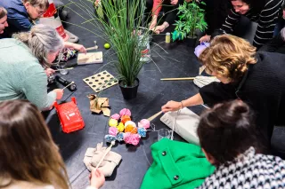Over K&C - ondernemers - groepje volwassenen op de grond aan het knutselen